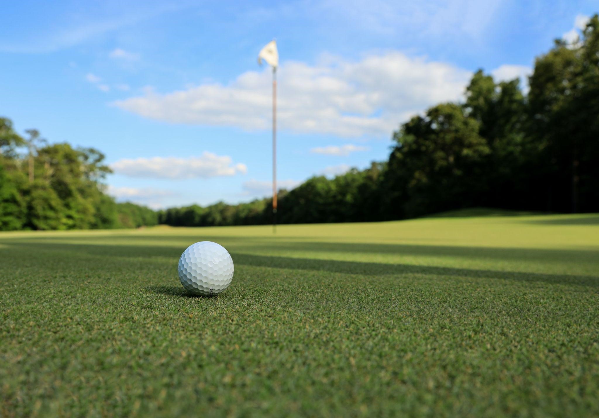 golfball on golf field, trees, flag